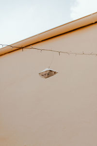 Low angle view of paper boat hanging on line against clear sky