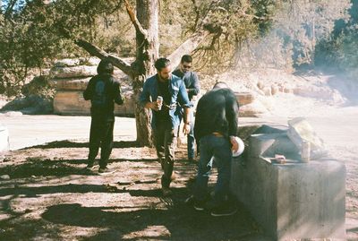 Rear view of people standing by tree trunk