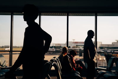Silhouette people at airport against sky