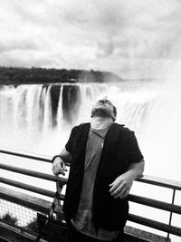 Man standing against waterfall