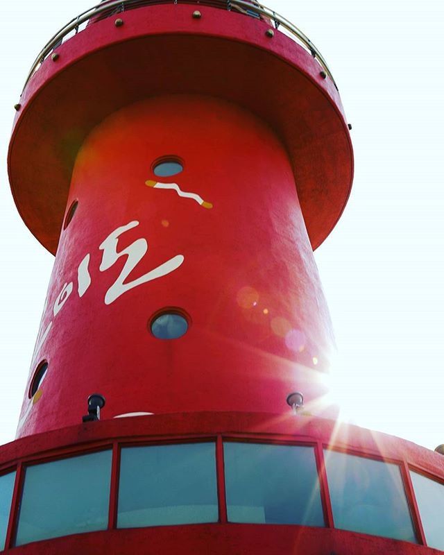 low angle view, red, architecture, built structure, building exterior, clear sky, guidance, protection, safety, tower, sky, no people, outdoors, day, sunlight, lighthouse, modern, security, direction, orange color