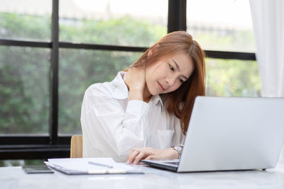 Businesswoman having neck pain while working in office