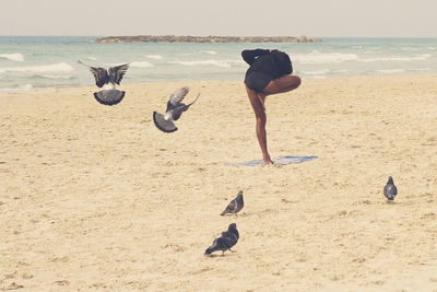 Full length of woman doing yoga at beach