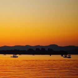 Boat sailing in lake against sky during sunset