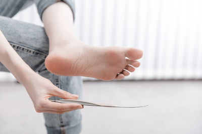 Low section of woman holding insoles by feet