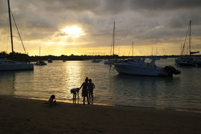 Sailboats moored on sea against sky during sunset