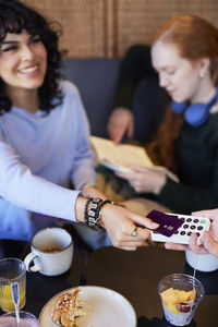 Young woman paying with card in cafe