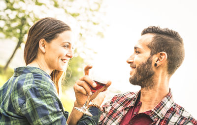 Close-up of couple smiling having red wine in glasses against clear sky