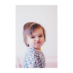 Portrait of cute baby girl puckering lips while standing against wall