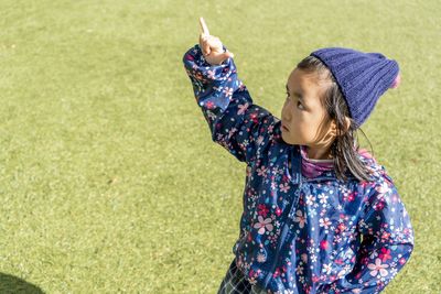 High angle view of girl pointing while standing on grass