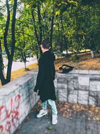 Rear view of boy walking by trees