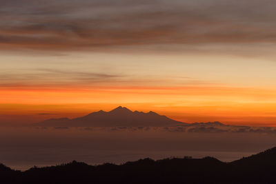 Scenic view of silhouette mountains against orange sky