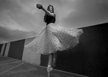 Full length of woman ballet dancing against sky