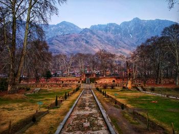 Railroad tracks amidst trees and mountains against sky