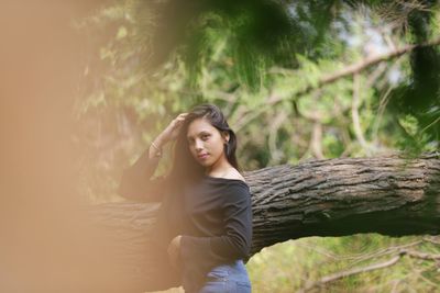 Portrait of woman standing by tree in forest