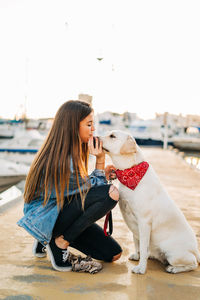 Woman with dog at harbor during sunset