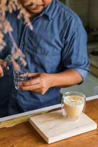 Midsection of man drinking glass on table