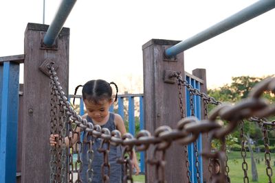 Girl standing on play equipment at park against clear sky