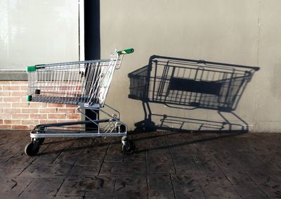 Side view of abandoned shopping cart against wall