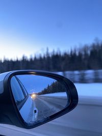 Close-up of side-view mirror against clear blue sky