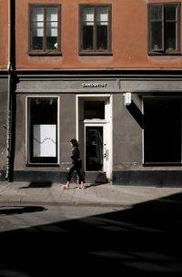 Side view of man running on footpath against building