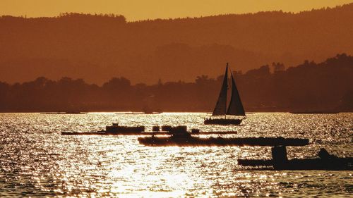 Silhouette sailboat in sea against sky during sunset