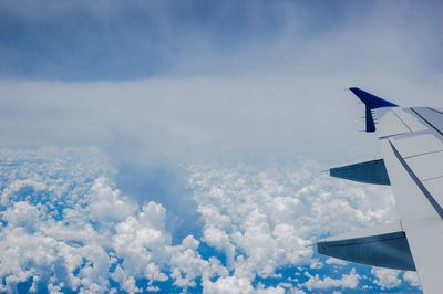 Airplane flying over clouds against sky