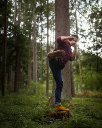 Full length of senior man on tree trunk in forest