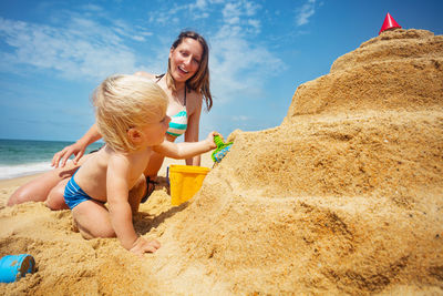 Side view of woman sitting on sand at beach