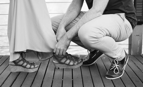 Low section of man tying woman's shoes