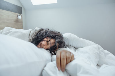 Amidst the soft folds of a plush robe and bedding, this woman takes a moment for herself