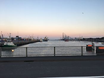 Pier at harbor against sky during sunset