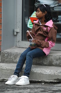 Young woman using mobile phone while sitting on steps