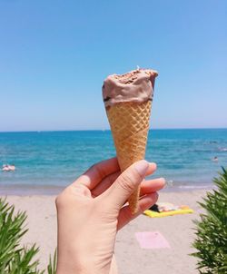 Close-up of hand holding ice cream against sea