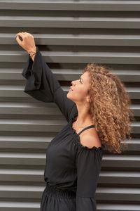 Side view of young woman standing against wall