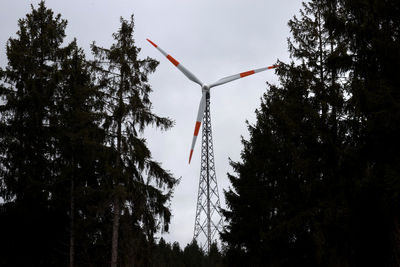 Low angle view of windmill and trees against sky