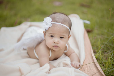 Portrait of cute baby girl wearing costume wing while lying on blanket