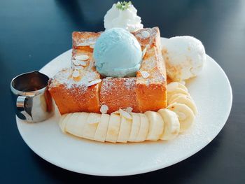 High angle view of bread and banana slices with ice cream and honey in plate