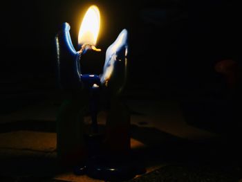 Close-up of lit candle in darkroom