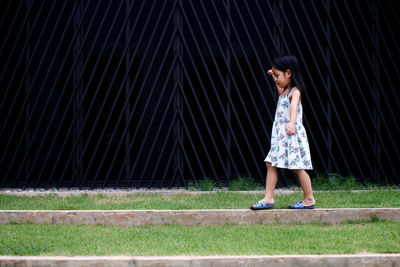 Side view of girl balancing on concrete structure at park