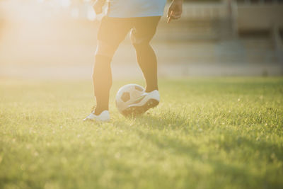 Low section of person playing soccer ball on grass