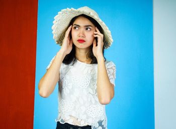 Portrait of woman standing against blue background