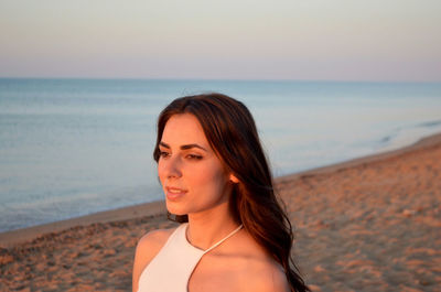 Portrait of smiling young woman on beach against sky