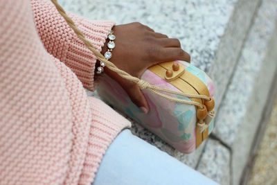 Cropped image of woman holding purse on retaining wall