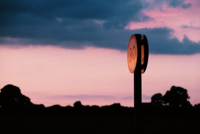 Low angle view of speed limit sign against sky during sunset