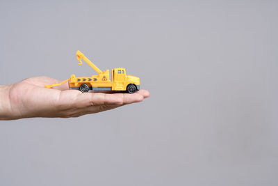 Close-up of hand holding toy car against gray background