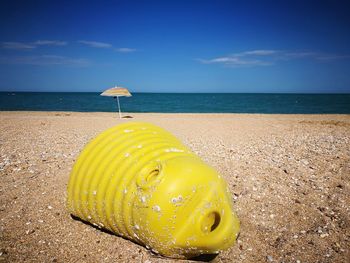 Yellow umbrella on beach against sky