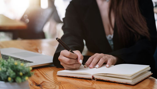 Midsection of woman reading book on table