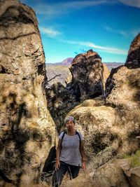 Man standing on rock against sky