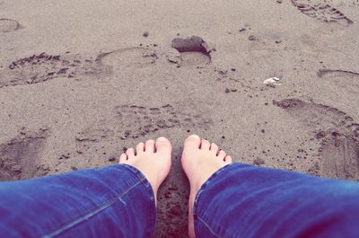 Low section of woman standing on sand